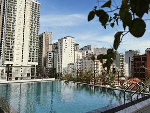 A swimming pool with a view of tall residential buildings in the background. - TUK TAK SPACES (Da Nang)