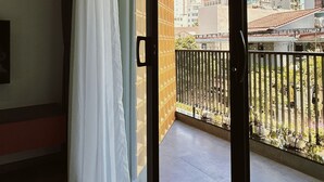 A balcony with a view of a cityscape, a sliding glass door, and a white curtain. - TUK TAK SPACES (Da Nang)