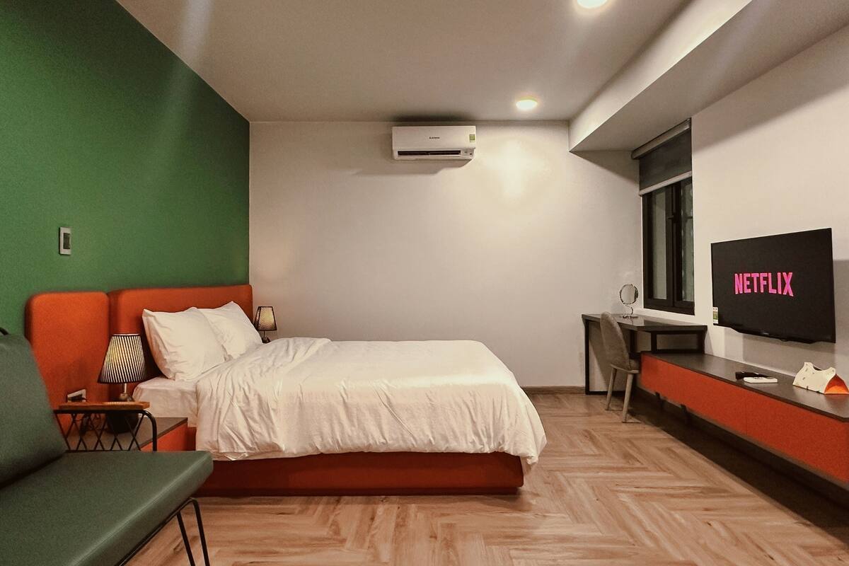 Ein modernes Hotelzimmer mit Bett, Schreibtisch, Fernseher und Klimaanlage.