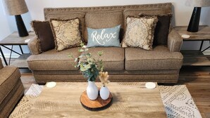 A brown sofa with decorative pillows, a wooden coffee table with vases, and a patterned rug. - Family Friendly Home~Pets Welcome-Fenced Yard (Clarksville)
