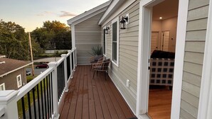 En træterrasse med gelænder, en dør ind til et rum og et lille bord med stole.