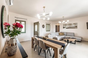 A spacious living room with a dining area, a sofa, and a chandelier.