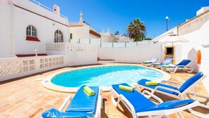 Uma área na beira da piscina com espreguiçadeiras e piscina.