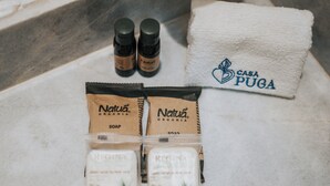 A bathroom setting with a white towel, two bottles of soap, and two soap bars labeled 'Natura Organía'. - Hotel Casa Puga (Oaxaca)