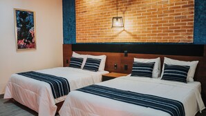 A hotel room with two beds, a brick wall, and a painting. - Hotel Casa Puga (Oaxaca)