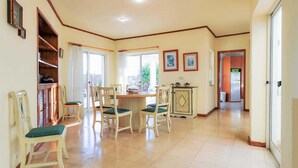 A spacious room with a dining area, a kitchen, and a hallway leading to a door. - Villa Brejos in Albufeira (Albufeira)