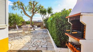 A patio with stone flooring, outdoor furniture, a barbecue grill, and a variety of plants. - Villa Brejos in Albufeira (Albufeira)