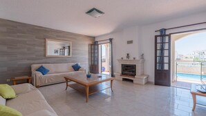 A spacious living room with a fireplace, a sofa, and a coffee table. - Villa Quinta do Jolu (Albufeira)