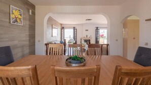 A dining area with a wooden table and chairs, a potted plant, and a view into another room with a fireplace. - Villa Quinta do Jolu (Albufeira)