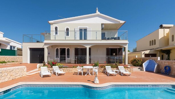A two-story house with a swimming pool, outdoor seating, and a stone wall. - Villa Quinta do Jolu (Albufeira)