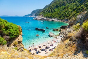 Une plage côtière bordée d’une eau turquoise et limpide, avec un terrain rocheux et une végétation luxuriante.