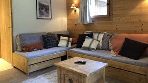 A cozy cabin-style room with two sofas, a small wooden table, and a framed picture on the wall. - Lauzière Dessus 22 - Crève Coeur (LES AVANCHERS VALMOREL)