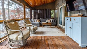 A cozy room with a wooden ceiling, a sofa set, wicker rocking chairs, and a television on a cabinet. - Lake Front Home w/Private Dock, Kayaks, Fire Pit & Hot Tub | Community Pool & Tennis (Waleska)