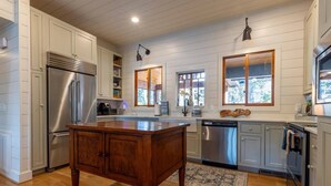A spacious kitchen with white cabinetry, a large island, stainless steel appliances, and a view through the windows. - Lake Front Home w/Private Dock, Kayaks, Fire Pit & Hot Tub | Community Pool & Tennis (Waleska)