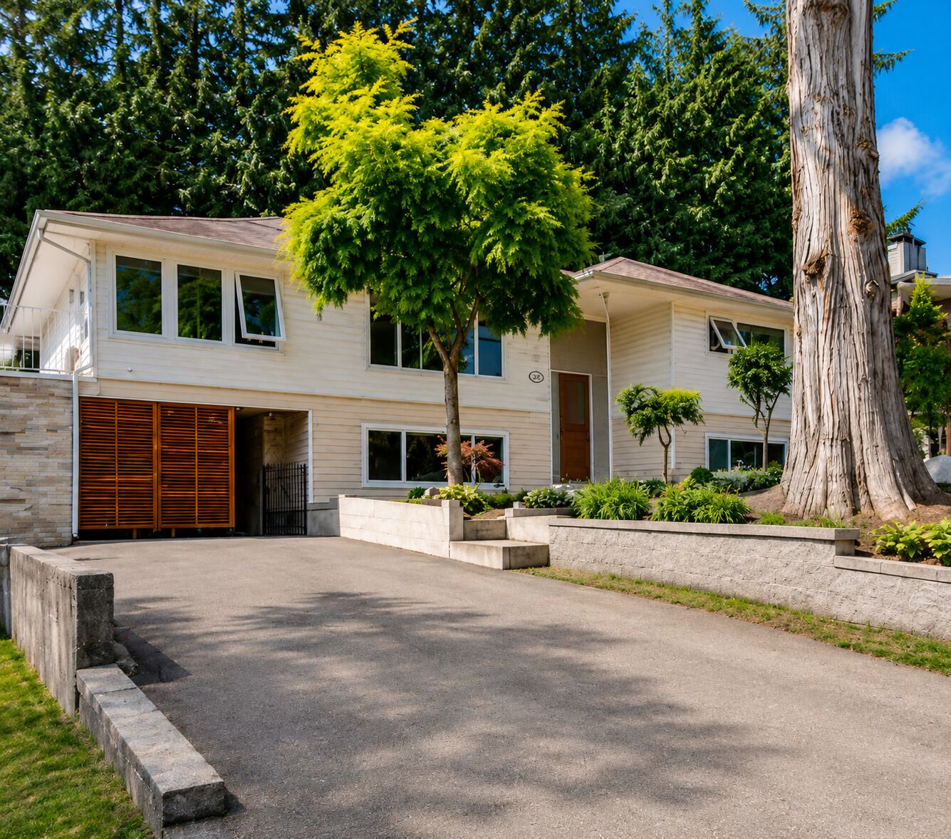 A two-story house with a garage, a driveway, and a large tree in the front yard.