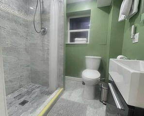 Une salle de bain avec douche, toilettes et lavabo.