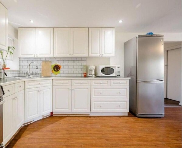 Enjoy cooking in this fully equipped kitchen with a refrigerator, microwave, and tiled backsplash.