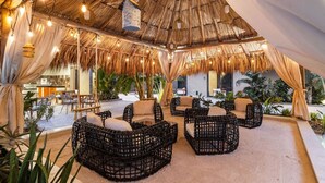 An outdoor seating area with wicker furniture and a thatched roof.