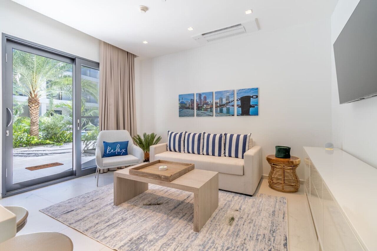 Un salon moderne comprenant un canapé, une table basse, un téléviseur et une porte-fenêtre coulissante donnant sur un balcon.