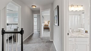 Ein Flur, der zu einem Schlafzimmer und Badezimmer mit einer Treppe führt.
