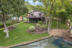 A two-story house with a covered porch, surrounded by a well-maintained lawn and a small pond.