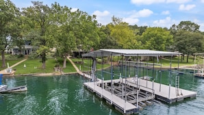 A dock with a covered seating area and a boat moored nearby.