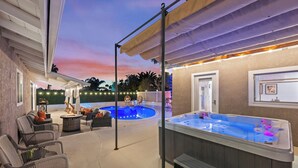 Ein überdachter Außenbereich mit Whirlpool, Sitzgelegenheiten und Pool.