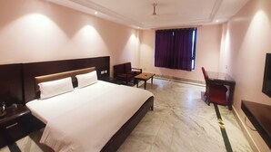 A hotel room with a large bed, a desk, a chair, and a television on the wall. - Hotel Shrinath Palace (Jhansi)