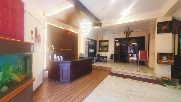 A hotel reception area with a wooden reception desk, a large aquarium, and a chandelier. - Hotel Shrinath Palace (Jhansi)