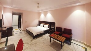 A hotel room with a bed, a desk, a chair, and a small table. - Hotel Shrinath Palace (Jhansi)
