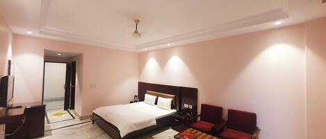 A hotel room with a bed, a desk, a chair, and a small table.