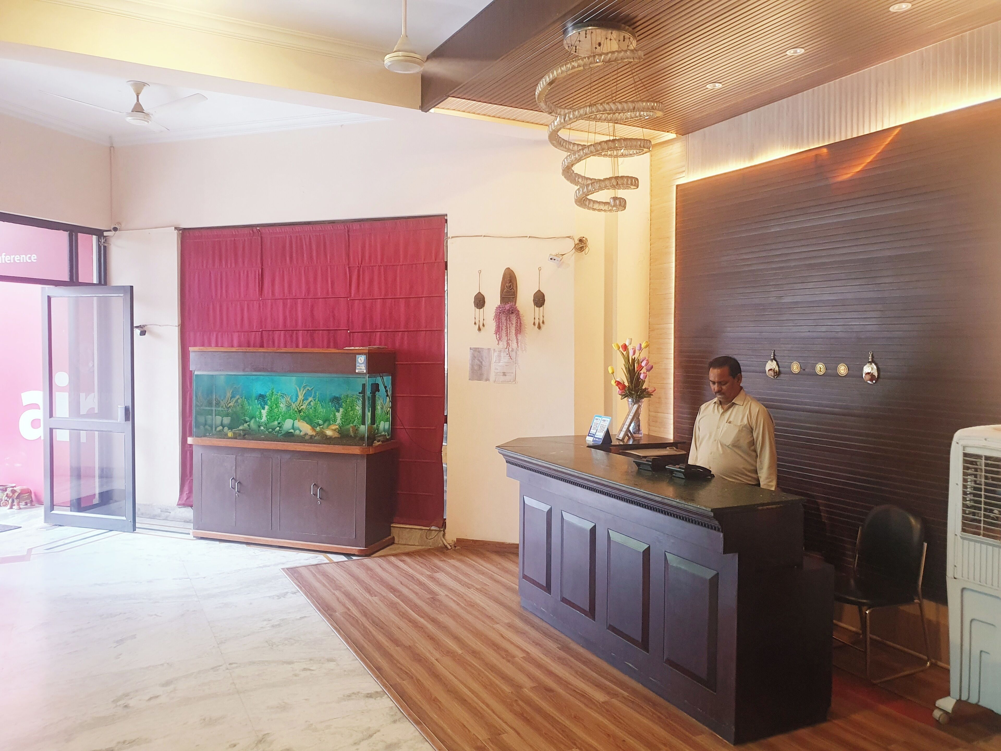 Un espace d’accueil avec un comptoir de réception en bois, un aquarium, un rideau rouge et un lustre.