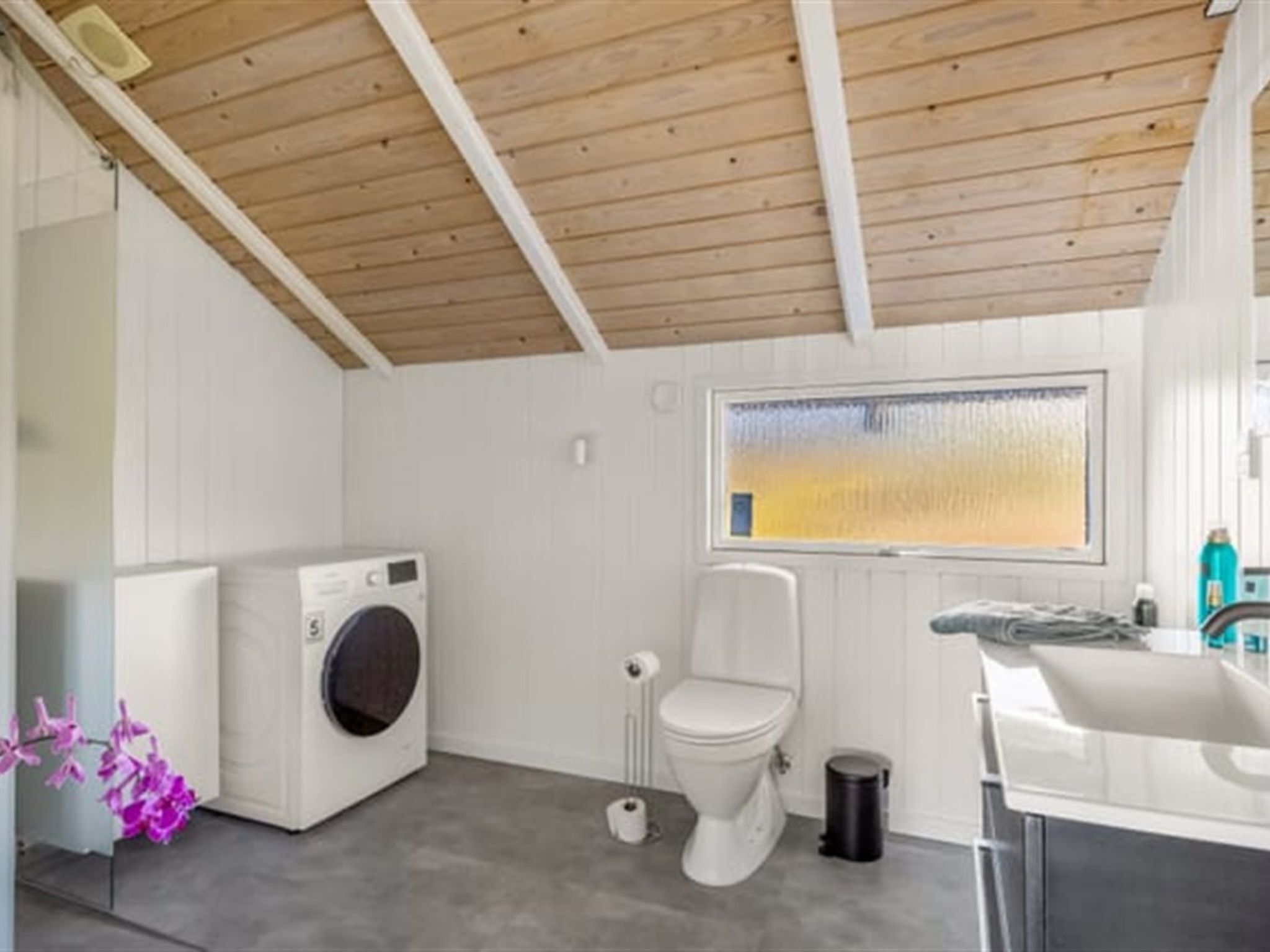 Ein kleines Badezimmer mit Waschmaschine, Toilette und Waschbecken.