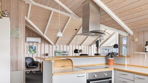 A modern kitchen with wooden beams, a built-in oven, and a dining area with a wooden table. - "Hera" - 200m from the sea by Interhome (Sydals)