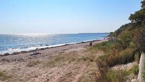 A beach with a clear sky, sandy shore, and sparse vegetation. - "Hera" - 200m from the sea by Interhome (Sydals)