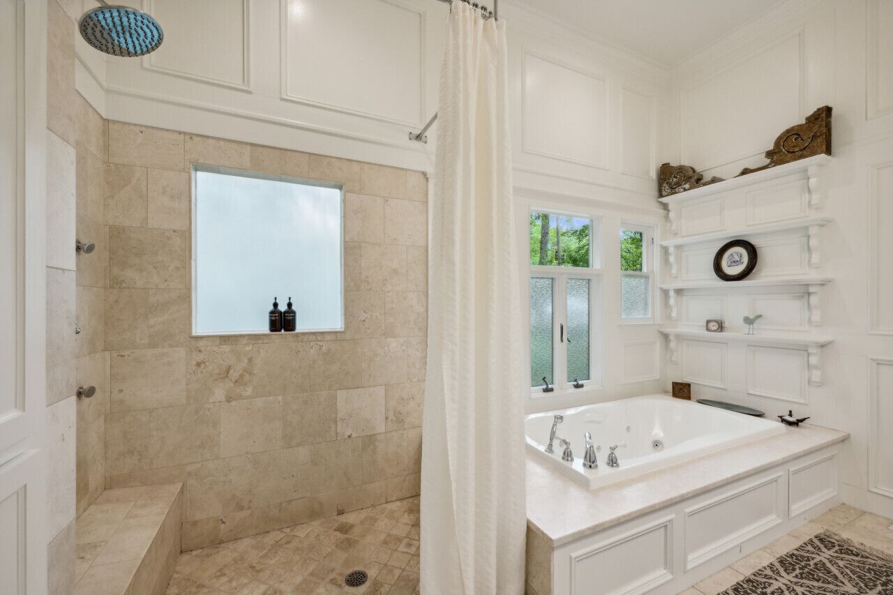 A bathroom with a large bathtub, a shower area, and a window providing natural light.