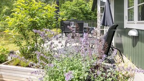 A patio with a wooden deck, outdoor furniture, and a variety of flowering plants. - "Tume" - 200m from the sea by Interhome (Nexø)