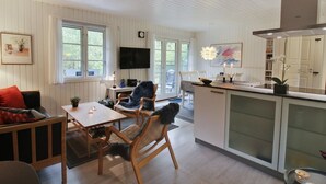 A modern kitchen with wooden cabinets, a dining area with a table and chairs, and a TV mounted on the wall. - "Tume" - 200m from the sea by Interhome (Nexø)