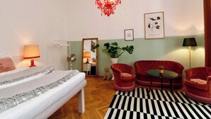 A hotel room with a bed, a chandelier, a mirror, a red sofa, a round table, and a black and white rug. - Romantic Urban Living (Vienna)