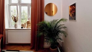 A room with a large window, a radiator, a potted plant, a round mirror, and a framed picture on the wall. - Romantic Urban Living (Vienna)