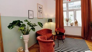 A room with a large plant, two red chairs, a black and white striped rug, and a window with curtains. - Romantic Urban Living (Vienna)