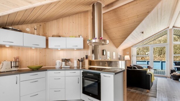 Een moderne keuken met witte kastjes, een roestvrijstalen afzuigkap en een groot eiland.