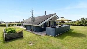 Een modern huis met een schotelantenne, een overdekte patio met tuinmeubilair en een verzorgd gazon.