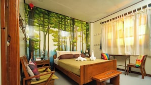 A bedroom with a large bed, a wooden chair, a small table, and a window with curtains.