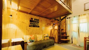 A cozy wooden cabin interior with a sofa, a small table, and a staircase.