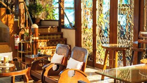 A cozy lounge area with wooden furniture, including two rocking chairs and a small table with a cup and saucer.