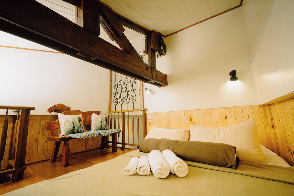 A wooden-framed room with a bed, a bench, and a table.