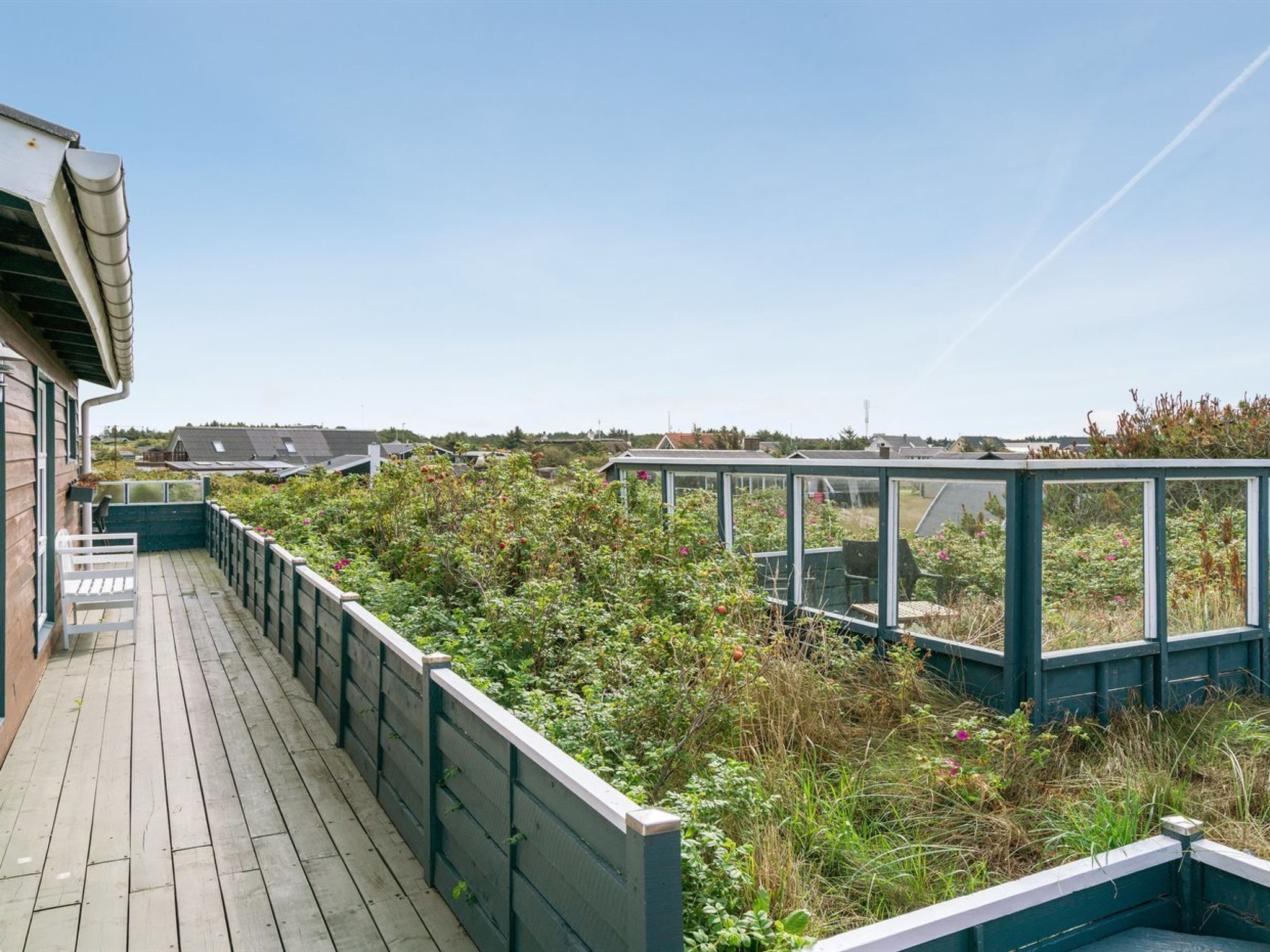 A wooden deck with a view of a garden and houses in the background.