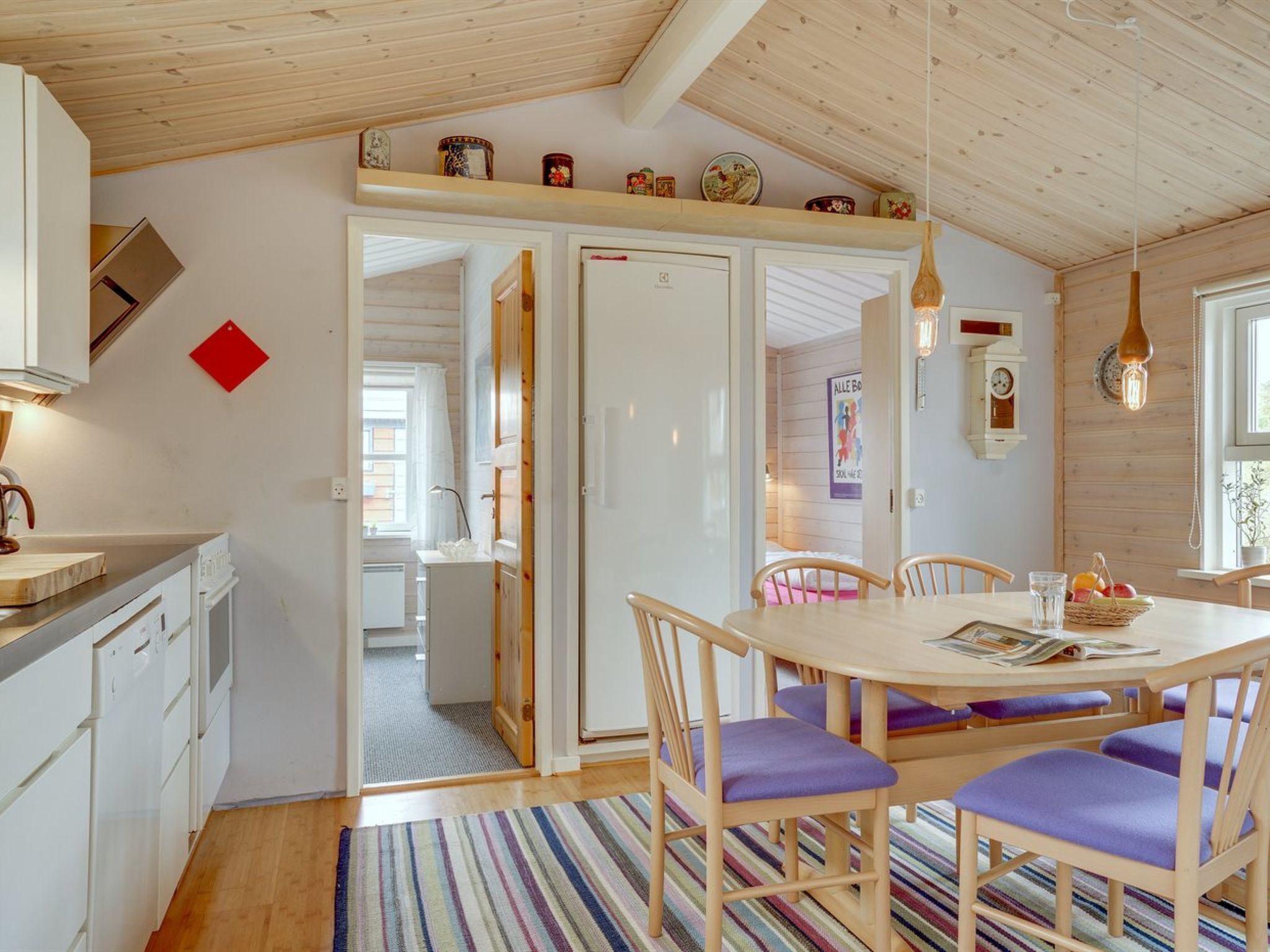 Et hyggeligt køkken med træskabe, et spiseområde med et bord og stole samt en køkkenø.