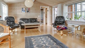 A spacious living room with a wooden ceiling, a black leather sofa, a coffee table, and a patterned rug. - "Stener" - 250m from the sea by Interhome (Thisted)